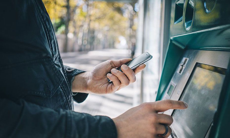 A man looking at his phone while at an ATM