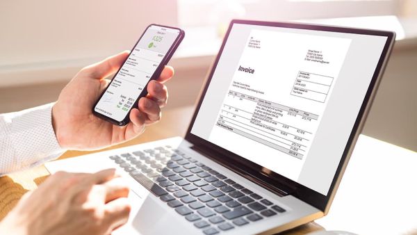 Man reviewing digital invoices to make payments on laptop and phone