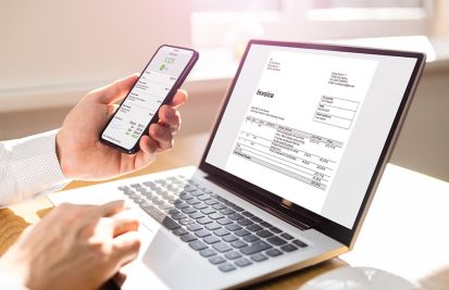 Man reviewing digital invoices to make payments on laptop and phone