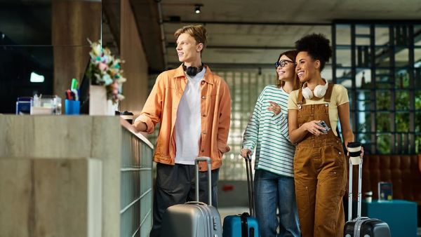 Three colleagues smile and chat while checking in at a hotel lobby