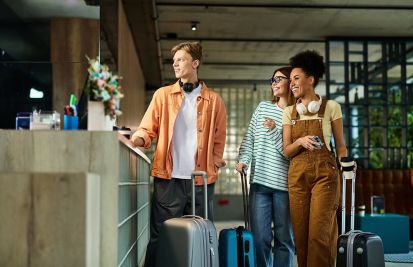 Three colleagues smile and chat while checking in at a hotel lobby