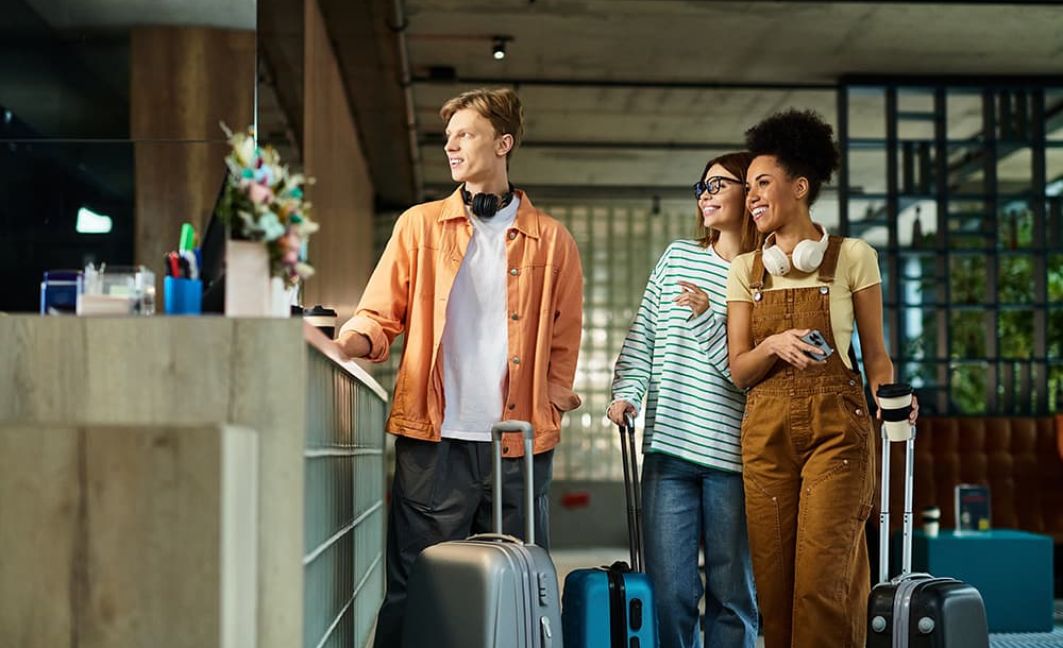 Three colleagues smile and chat while checking in at a hotel lobby