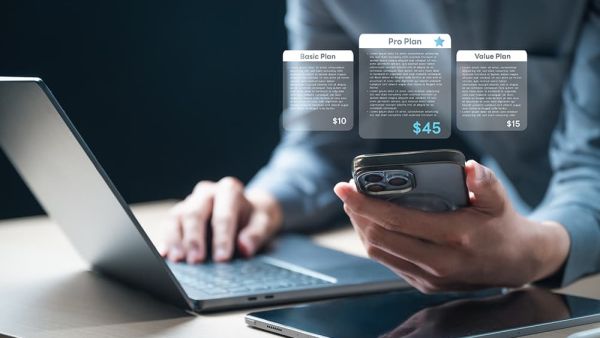 recurring billing with man holding a mobile and typing on laptop