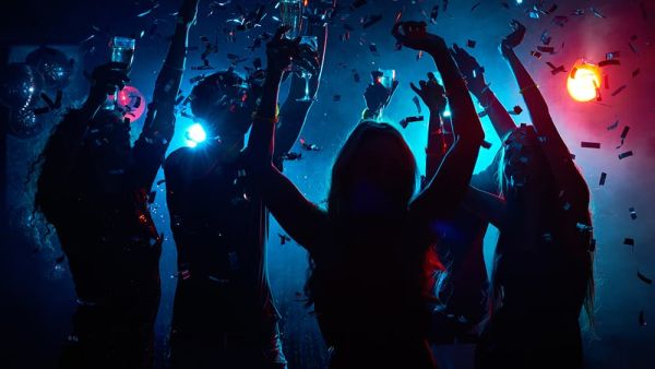 Young people with raised glasses having fun and clubbing