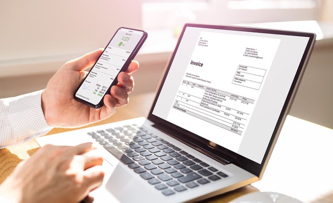 Man reviewing digital invoices to make payments on laptop and phone