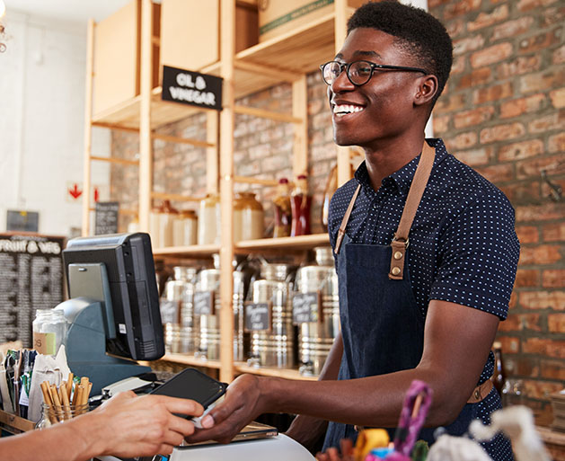 A male barista accepting card payments using North's POS systems