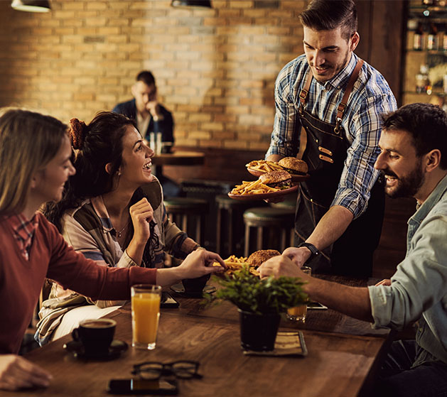 A waiter delivering burgers to a table at a franchise restaurant 