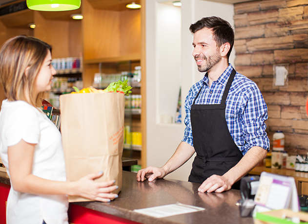 A grocer handing over groceries to a customer