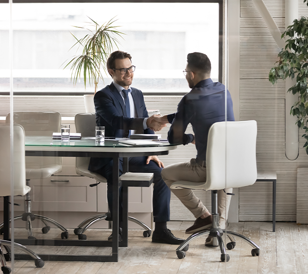 Two businessmen shaking hands over a desk