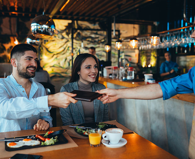 A couple on a date taking the bill from a waiter 