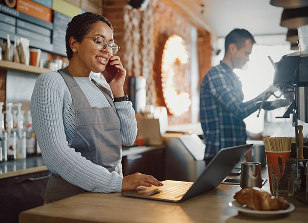 A coffee shop owner reviewing financial reports on her laptop using North's merchant portal