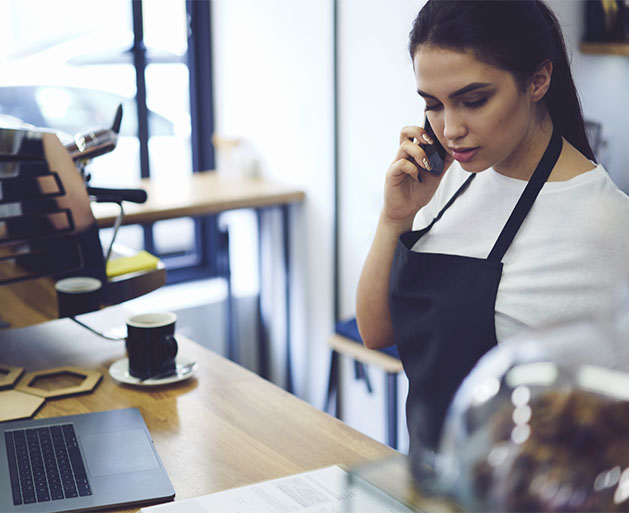 A coffee shop employee on her phone, looking at customer management tools provided by North's POS systems