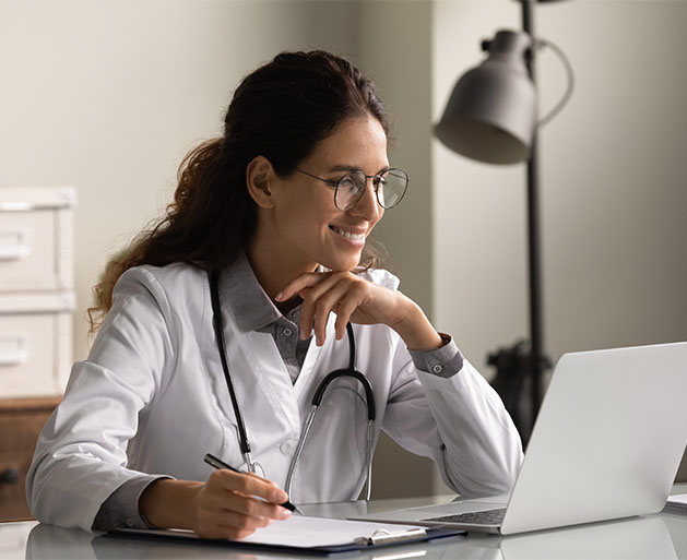 A healthcare professional on a laptop managing staff