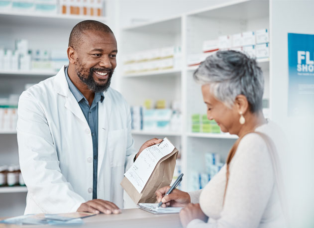 A pharmacist handing a prescription to a customer