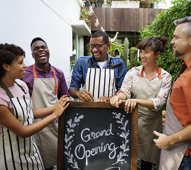 Bakery workers gathered around their shop's sign laughing