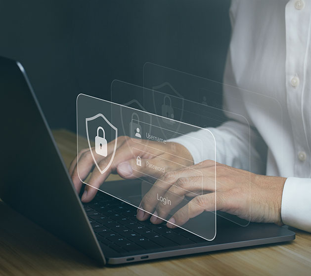 Hands typing on a laptop with holographic security icons floating above