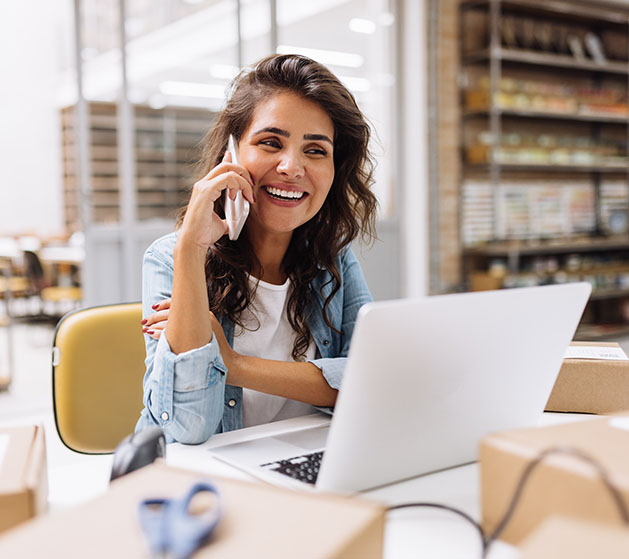 A female business owner own the phone laughing at her desk