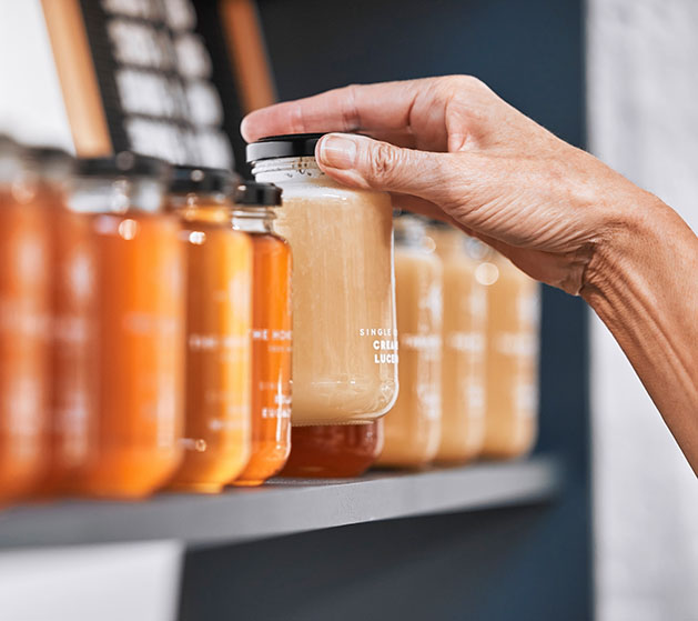 A hand placing jars of coffee up on a shelf