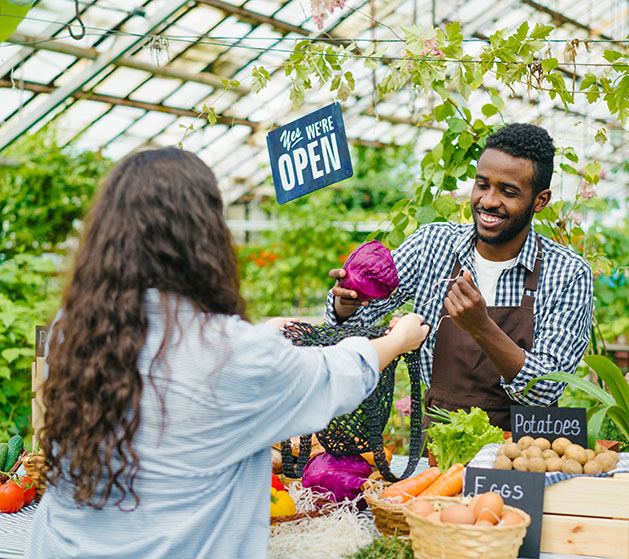 A grocer placing a vegetable into a womans' bag