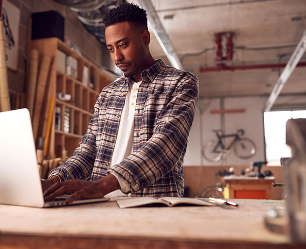 A male business owner looking over his business performance with North's merchant services on a lap top 